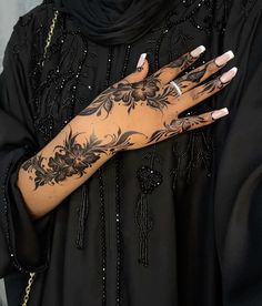 a woman with tattoos on her arm and hand is wearing a black dress holding a gold chain