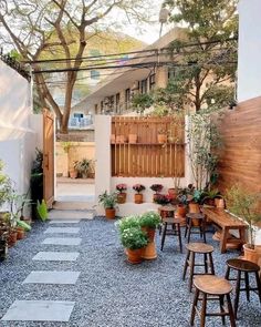 an outdoor patio with potted plants and wooden stools on the side of it