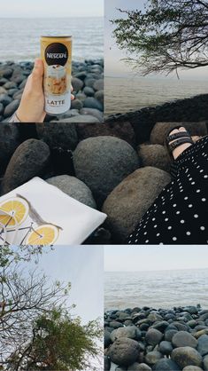 a person holding up a can of lemonade next to the ocean and rocks in front of them