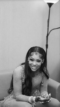 a woman sitting on top of a couch in front of a lamp and smiling at the camera