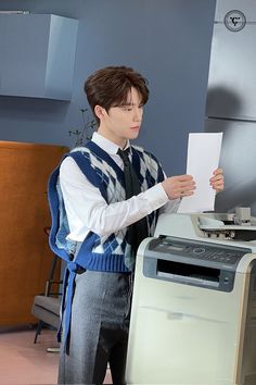 a young man standing in front of a washing machine and holding up a piece of paper