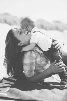 a woman holding a baby on the beach