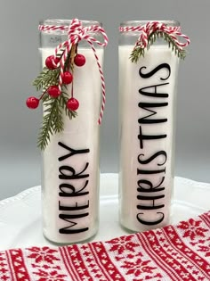 two christmas candles sitting on top of a white plate