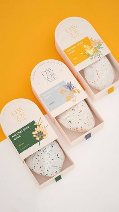 three boxes with different types of soaps in them on a yellow and white background