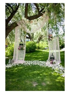 an outdoor wedding ceremony with flowers and birdcages on the grass, surrounded by trees