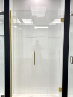 a bathroom with a glass shower door and white tile flooring on the side wall