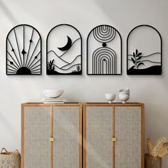 three metal art pieces on the wall next to a cabinet with bowls and vases