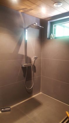 the shower head is mounted to the wall in the bathroom, while the light shines through the window