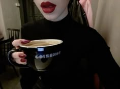 a woman with makeup holding a cup of coffee