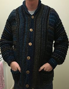 a man standing in front of a mirror wearing a black and blue cardigan sweater