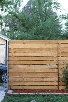 a large wooden fence in front of a house with a car parked on the side