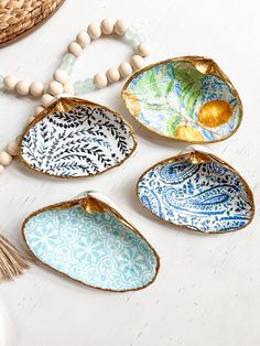 four ceramic dishes with beaded necklaces on top of white wooden table next to basket