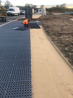 two men working on the side of a road with metal grates in front of them