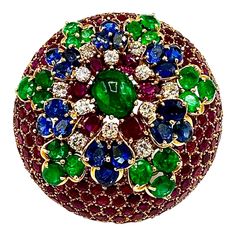 This brooch has an amazing array of colors! The brooch contains over 35.00 carats in combination of all the Diamonds and Gemstones. This is designed in a domed shape, with honeycomb shaped settings for the round Rubies, leading into a star pattern of oval, round and cabochon Emeralds, oval Sapphires, round brilliant Diamonds, and oval Rubies. All of these Gemstones display bright and vibrant colors. The brooch measures 1.80 inches in diameter, and features a double pin closure in the back. The back of the brooch is marked "Made in France". Offered by Charles Schwartz & Son Jewelers. Stone breakdown: 12 Diamonds - 1.32 carats 187 Rubies - 22.92 carats 18 Sapphires - 5.00 carats 19 Emeralds - 6.05 carats Luxury Oval Cabochon Brooch, Honeycomb Shape, David Webb, Gold Brooches, Sapphire Diamond, Star Patterns, Honeycomb, Ruby, Emerald