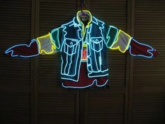 a lighted jacket hanging on the wall in front of a door with shutters behind it