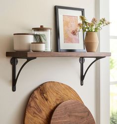 a shelf with two wooden boards on it and some flowers in vases next to it