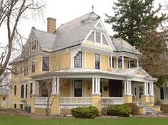 a large yellow house sitting on top of a lush green field