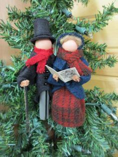 two dolls sitting on top of each other in front of a christmas tree with an open book