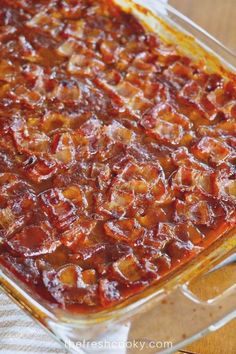 a casserole dish with meat and sauce in it on a wooden table top