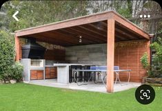 an outdoor kitchen and grill area in a backyard with wood sidings on the walls