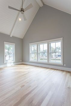 an empty room with wood floors and two windows in the ceiling is seen from across the room