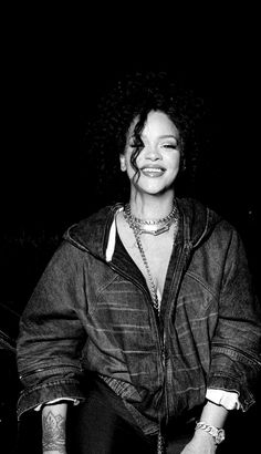 a black and white photo of a woman with tattoos on her arm, smiling at the camera