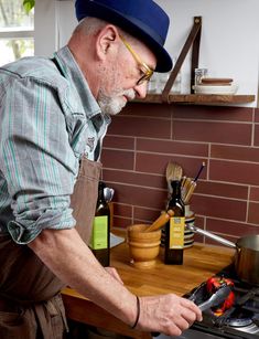 an older man wearing glasses and a blue hat is working on something in the kitchen