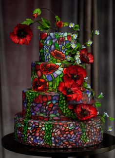 a multi - tiered cake decorated with red flowers and green leaves