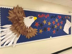 an eagle and stars bulletin board hanging on the wall in a school hallway with writing