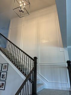 a staircase with chandelier and pictures on the wall