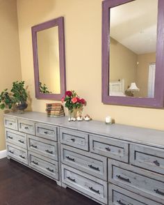 a dresser with two mirrors and flowers on it