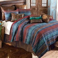 a bed with a colorful comforter and pillows in a room next to a cowhide rug