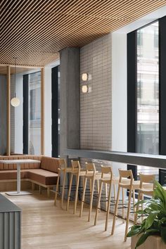 an empty restaurant with wooden tables and chairs in front of large windows that look out onto the city