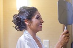 a woman is holding a hairdryer in her hand and looking at the mirror