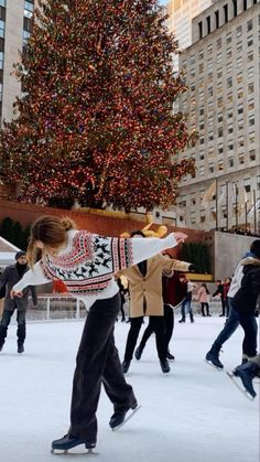 people skating on an ice rink in front of a christmas tree