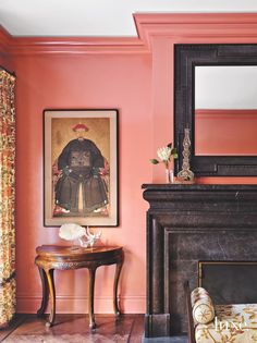 a living room with pink walls and a painting on the wall above a fire place