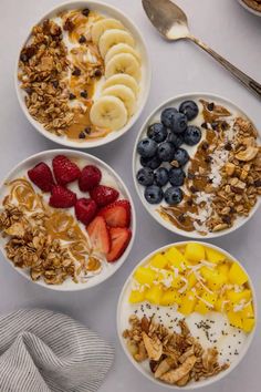 four bowls filled with granola, fruit and yogurt