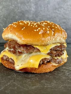 a cheeseburger with meat and melted cheese on a black surface, ready to be eaten