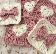 crocheted pink and white hearts with bows on them are sitting on a bed