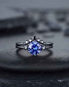 a ring with a blue stone in the center on top of a black rock surface