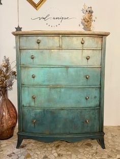 a blue dresser with two vases on top of it and a gold heart above it