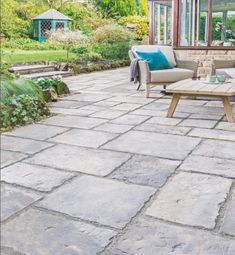 an outdoor patio with chairs, table and couches in the middle of it is surrounded by greenery