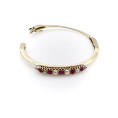 This is part of Chairish’s Fine Jewelry assortment.  The centrepiece of this charming bracelet was most likely once a brooch, converted at some point into a stylish bangle. It contains six round half pearls and five oval-shaped cabochon rubies, prong-set into an alternating pattern, that has been beautifully incorporated into a knife edge bracelet. Each end of the bar culminates in triangular points, which marry into the knife edge for a clean and sophisticated look. The 14k gold bangle has a sa Elegant Multi-stone Bangle Bracelets, Elegant Oval Cabochon Cuff Bracelet, Elegant Oval Cuff Bracelet For Formal Occasions, Elegant Multi-stone Bangle For Anniversary, Elegant Multi-stone Cuff Bangle Bracelet, Yellow Gold Cabochon Bracelets For Weddings, Elegant Cabochon Cuff Bangle Bracelet, Classic Formal Pearl Bangle Bracelet, Formal Multi-stone Bangle Fine Jewelry