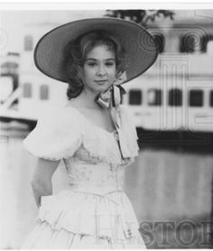 black and white photograph of a woman in a dress with a large hat on her head