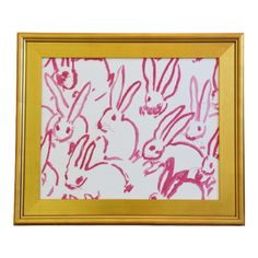 a painting with pink ink on white paper in a gold frame, depicting many rabbits