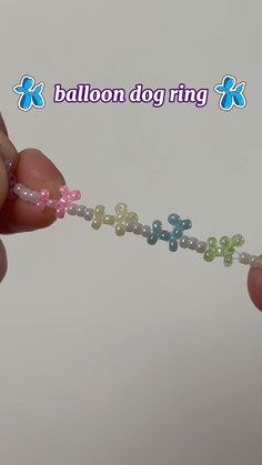 a person is holding a beaded bracelet with flowers on it and the words balloon dog ring