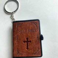 a leather keychain with a bible on it and a cross in the center