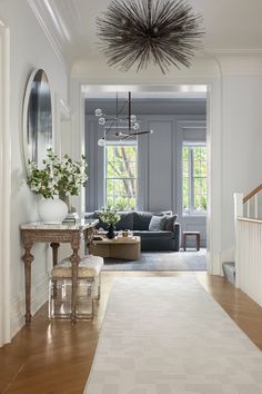 a living room filled with furniture and a chandelier hanging over the top of a wooden floor