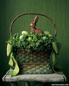 a basket filled with green vegetables and a rabbit figurine sitting on top of it