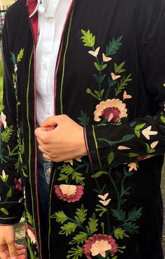 a man wearing a black jacket with flowers on it